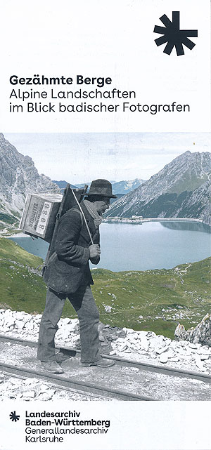 Der Flyer zur Ausstellung zeigt einen Mann mit einer Kiepe auf dem Rücken vor einem Bergsee. © GLA Karlsruhe